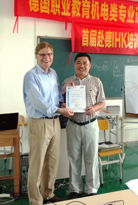 a German and a Chinese presenting a certificate